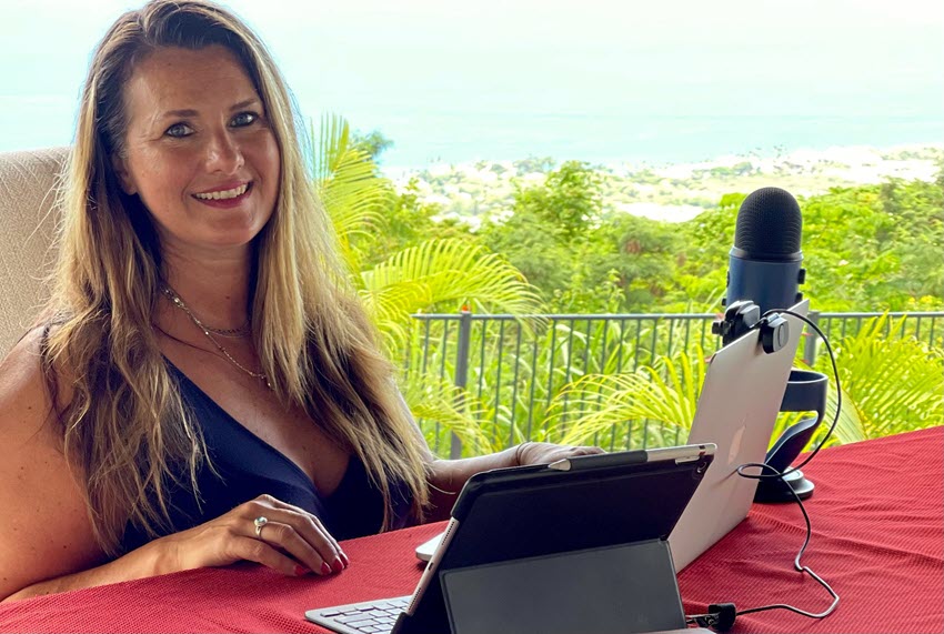 Photo of Jen Gilchrist with a laptop and podcasting microphone